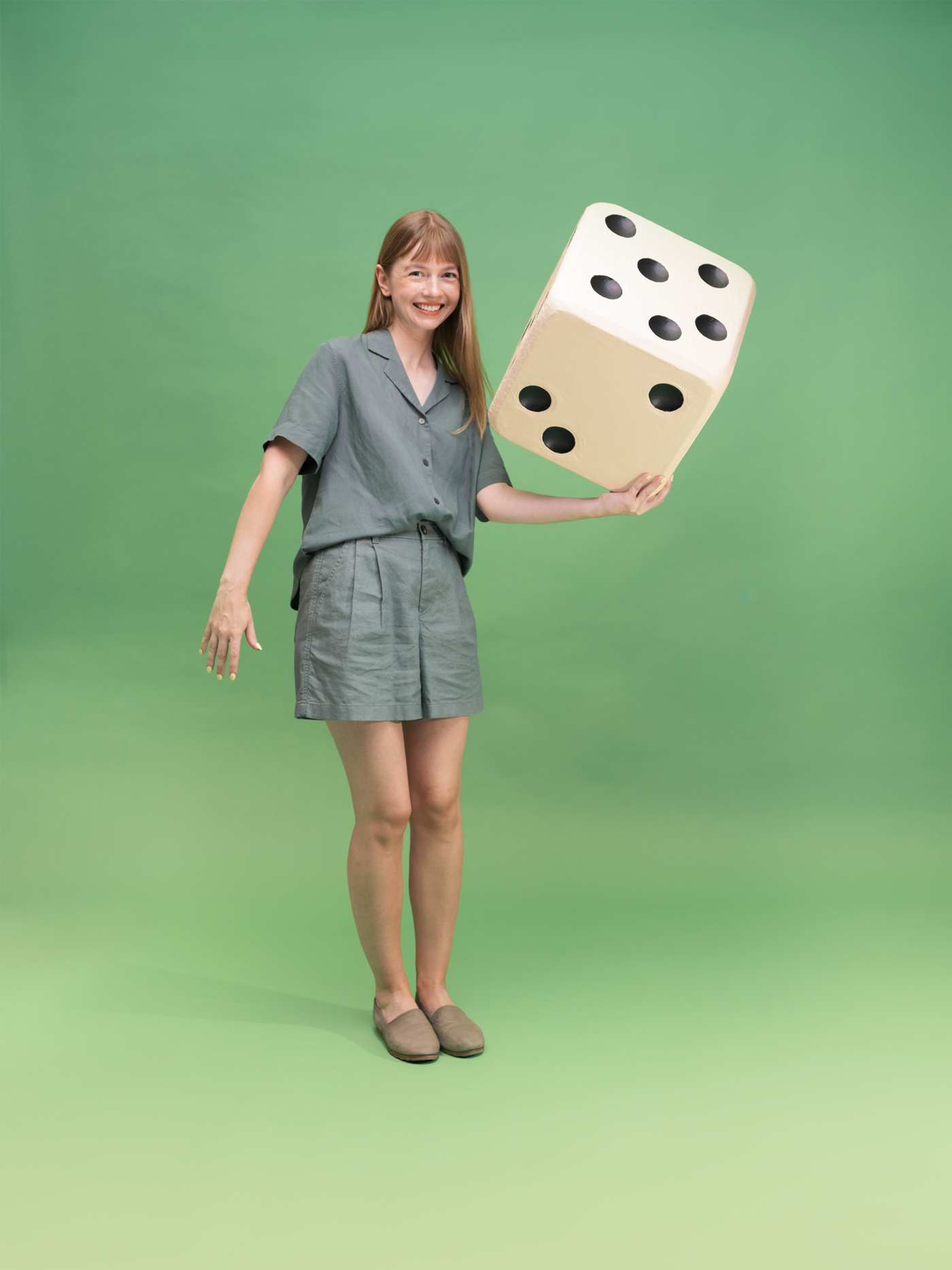 portrait of Dorota Pankowska holding a giant dice prop and smiling