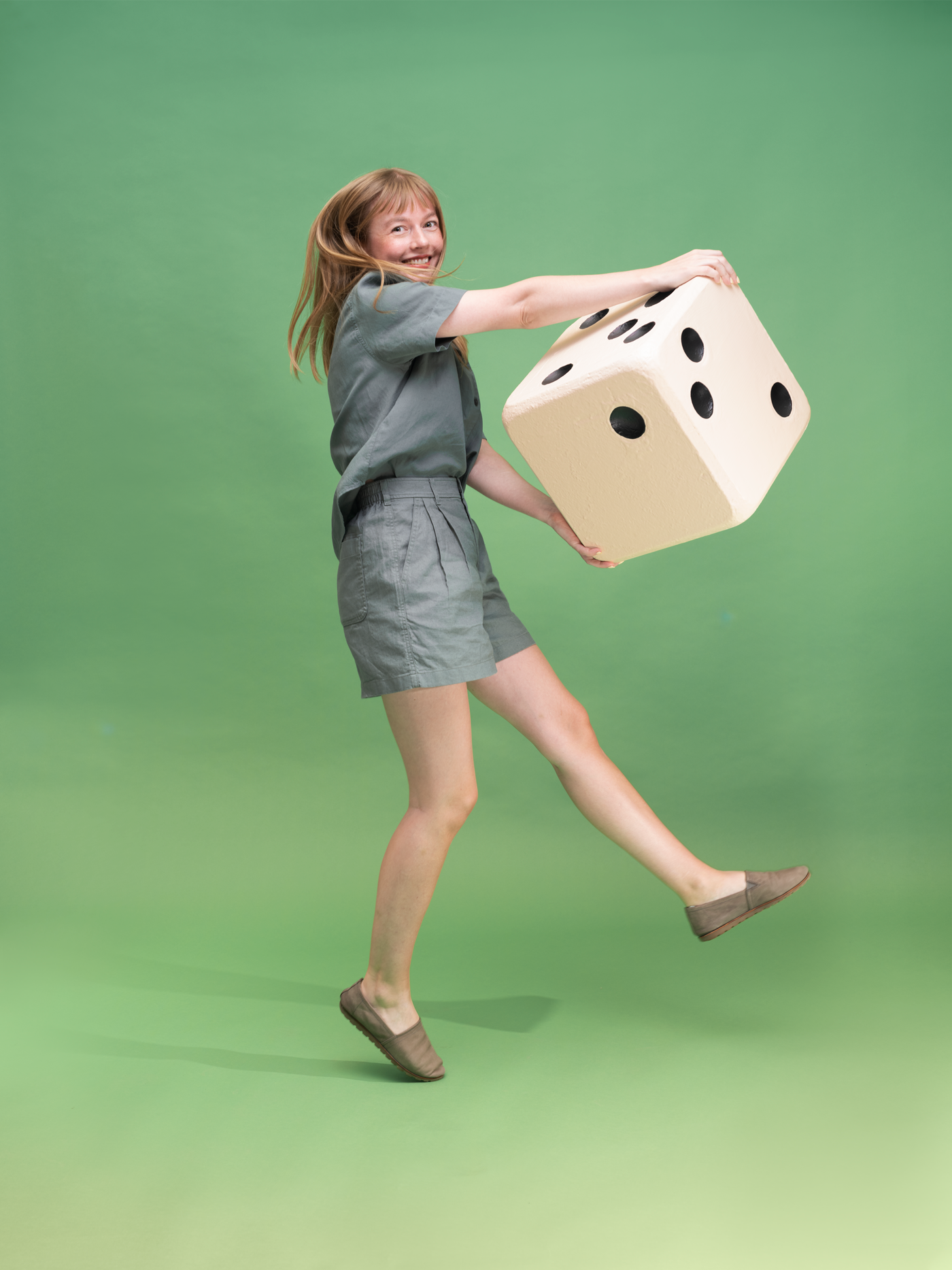 portrait of Dorota Pankowska holding a giant dice prop and jumping