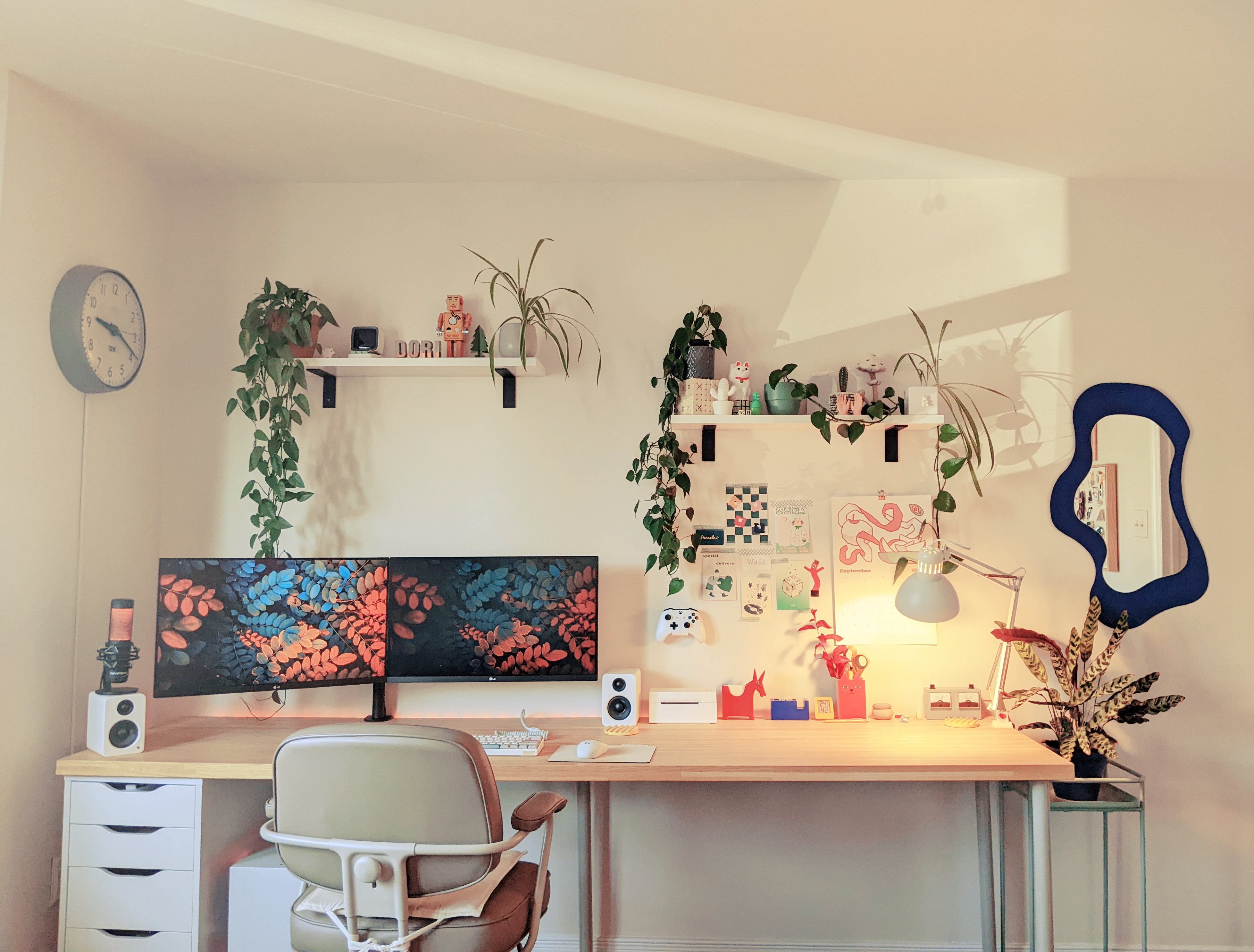 a cosy work station with two monitors and plants